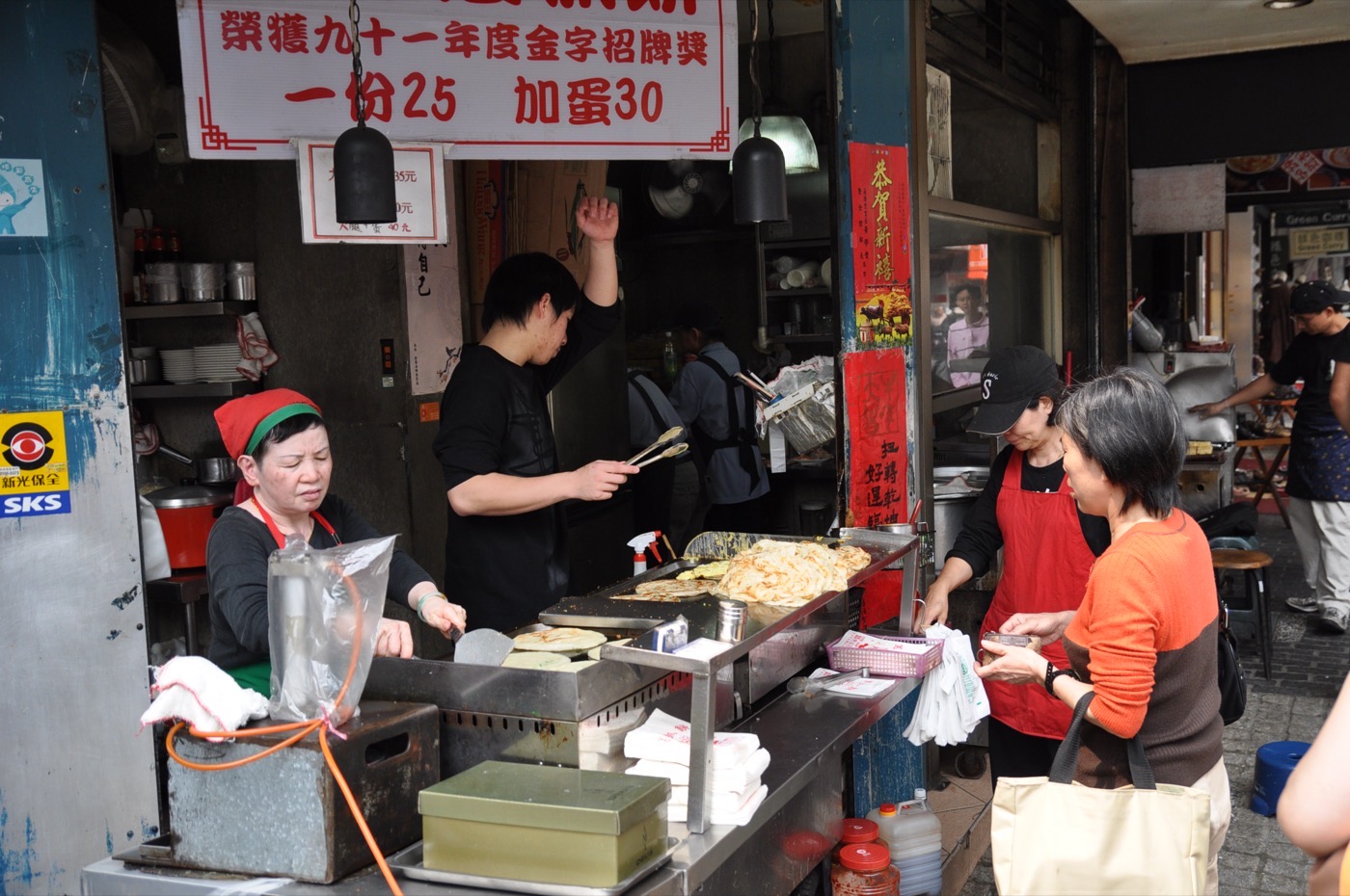 A vendor pan-frying a flaky scallion pancake (蔥抓餅) on a Taipei street